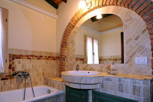 La salle de bains est pourvue d'un lavabo, d'une baignoire et d'un miroir. dans l'établissement Erboli Residence, à Cavriglia