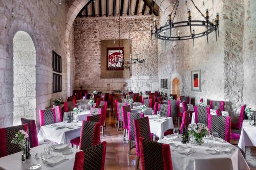 une salle à manger avec des tables blanches et des chaises roses dans l'établissement Parador de Alarcón, à Alarcón