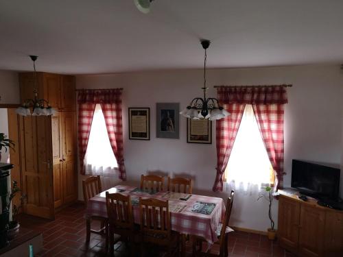 a dining room with a table and chairs and two windows at Szentgyörgyvölgy Vendégház Őrség in Szentgyörgyvölgy