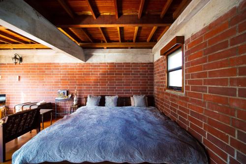 a brick bedroom with a bed in a brick wall at 猫とピアノと星空のリゾートブティックコテージ -Starry Forest Cottage Okinawa- in Onna