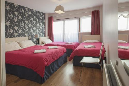 two beds in a room with red sheets at Two Ducks Hostel in Rome