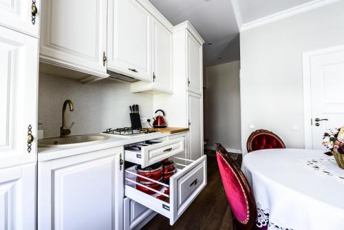 kuchnia z białymi szafkami, zlewem i łóżkiem w obiekcie Nostalgia Apartment w Kłajpedzie