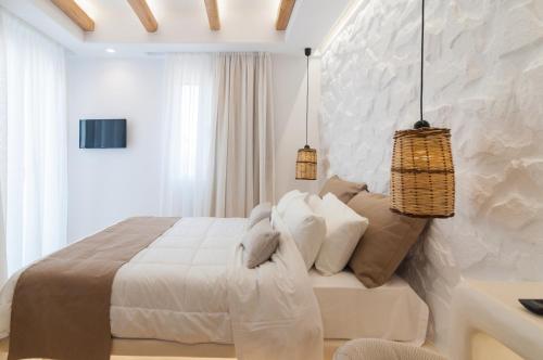 a white bedroom with a large bed and two pendant lights at Villa Adriana Hotel in Agios Prokopios
