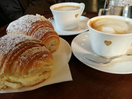 two plates of croissants and cups of coffee on a table at Flai Home in Vico Equense
