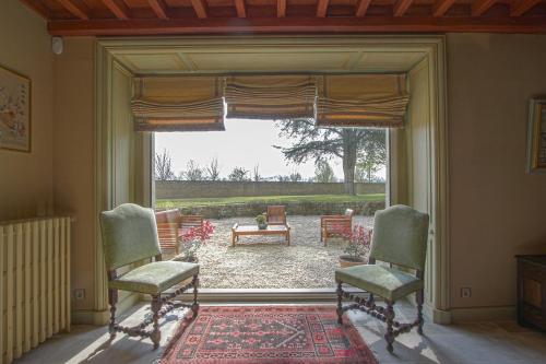 une chambre avec deux chaises et une grande fenêtre dans l'établissement Château de Monceaux 5mn de Bayeux proche Mer, à Bayeux
