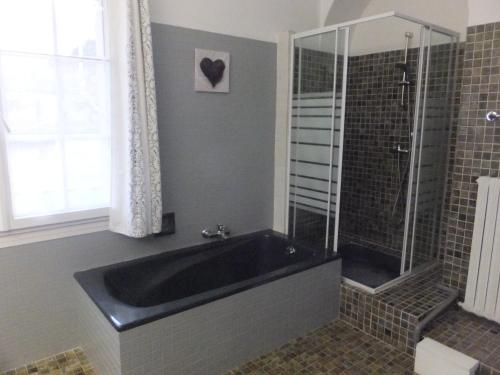La salle de bains est pourvue d'une baignoire noire et d'une douche. dans l'établissement Bastide du Bonheur Saint Donat, à Gréoux-les-Bains