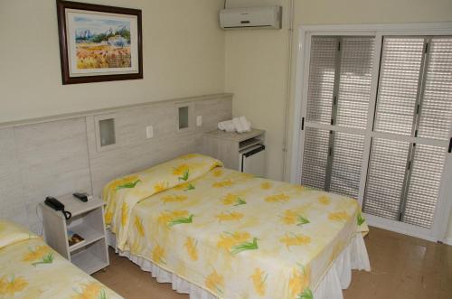 a bedroom with two beds and a window at Dona Adelia Hotel e Restaurante in Flores da Cunha