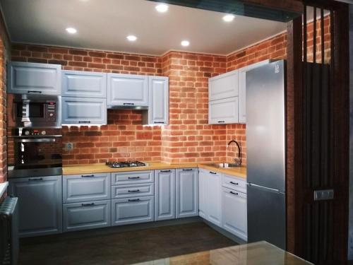 een keuken met witte kasten en een bakstenen muur bij LOFT - Interior design apartments in Oral