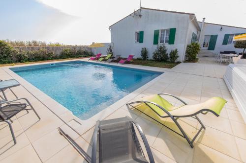 une piscine avec des chaises et une maison dans l'établissement Villa des Jaulaines, Villa en bord de mer - Ile de Ré, à Sainte-Marie de Ré