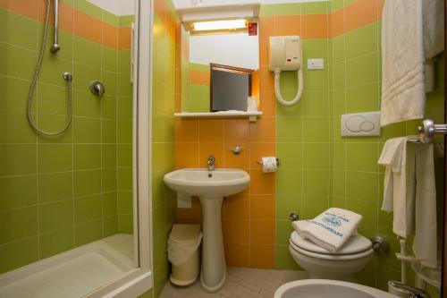 La salle de bains est pourvue de toilettes, d'un lavabo et d'une douche. dans l'établissement Hotel Eden, à Grottammare