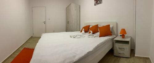a bedroom with a large white bed with orange pillows at Airport view Apartment in Belgrade
