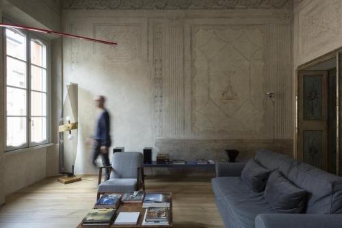 a man walking in a living room with a couch and a table at Appartamento affrescato 180mq in palazzo del 600 a Mantova in Mantova