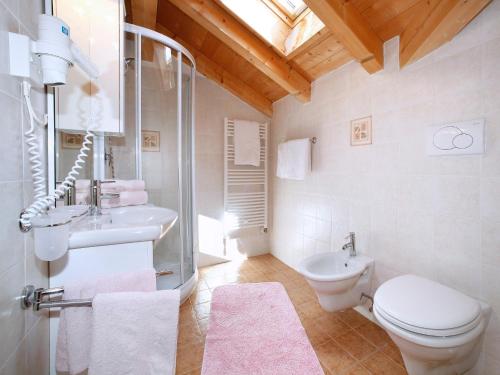ein weißes Bad mit einem WC und einem Waschbecken in der Unterkunft Garni Ortles in Wolkenstein in Gröden