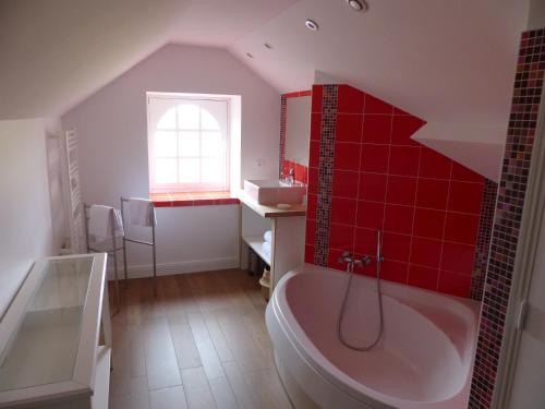 La salle de bains est pourvue de carrelage rouge, d'une baignoire et d'une fenêtre. dans l'établissement La commanderie aux portes de Chambord, à Huisseau-sur-Cosson