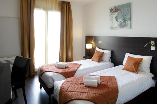 een hotelkamer met 2 bedden en een raam bij L'EPI HOTEL in Épernon