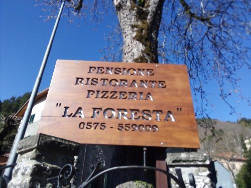 a sign on a tree in front of a building at La Foresta Albergo Ristorante Pizzeria in Badia Prataglia