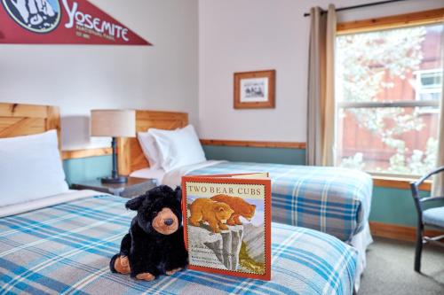 a stuffed dog sitting on a bed with a book at Evergreen Lodge at Yosemite in Groveland