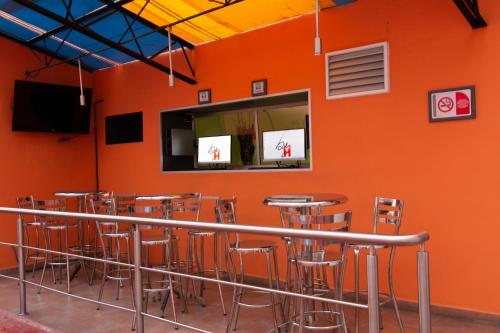 a bar with stools in a room with an orange wall at Hotel H - Piet Adults Only in Mexico City