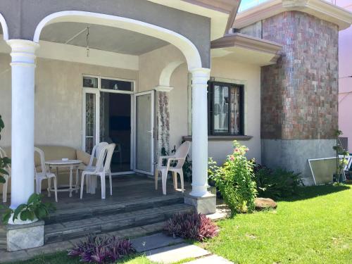 a house with a porch with a table and chairs at Cardamon Villa is a 2 bedroom with 1 bathroom and seperate toilet detached house with AC and swimming pool , 5 minutes walk from Flic en Flac public beach in Flic-en-Flac