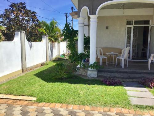 a house with a porch with a table and chairs at Cardamon Villa is a 2 bedroom with 1 bathroom and seperate toilet detached house with AC and swimming pool , 5 minutes walk from Flic en Flac public beach in Flic-en-Flac