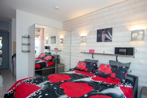 カップ・ダグドにあるCap d'Agde Naturisteのベッドルーム1室(ベッド2台、赤と黒の枕付)