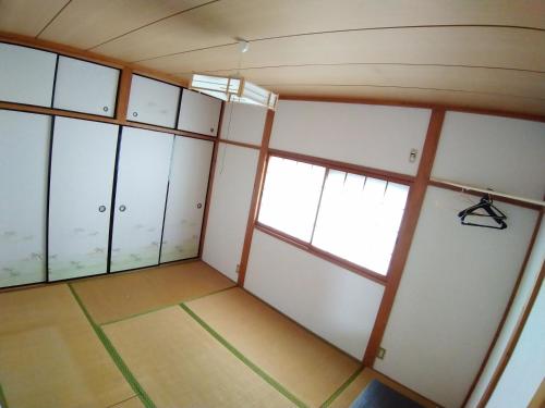 an empty room with white cabinets and a window at ツバメハウス in Tenri