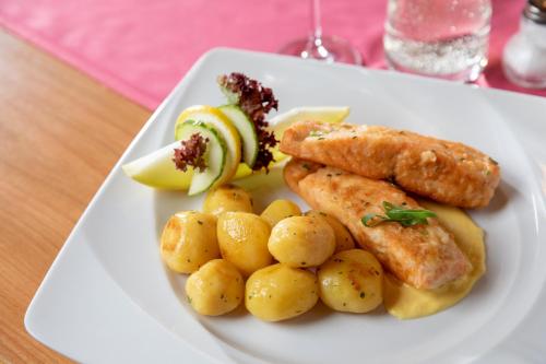 a plate of food with fish and potatoes on a table at Hotel-Restaurant Straussen in Harburg