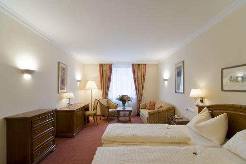 a hotel room with two beds and a desk at Vergeiner's Hotel Traube in Lienz