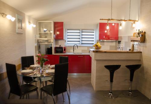 a kitchen with red cabinets and a table with chairs at Vacation house K&I in Peroj