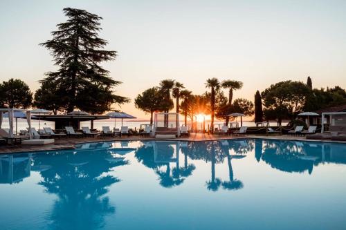 a swimming pool with the sun setting in the background at Splendido Bay Luxury Spa Resort in Padenghe sul Garda
