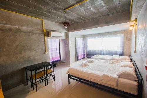 a bedroom with a large bed and a table at The Sky Loft Hotel in Pathum Thani