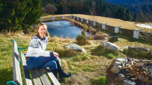 a woman sitting on a bench next to a pond at Schloss Berg Klösterle in Zedlitzdorf