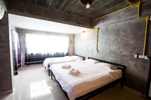 two beds in a room with a window at The Sky Loft Hotel in Pathum Thani