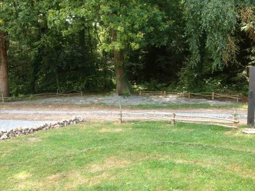 a wooden fence in a field with a tree at Roulotte du Petit Bois in Theillement