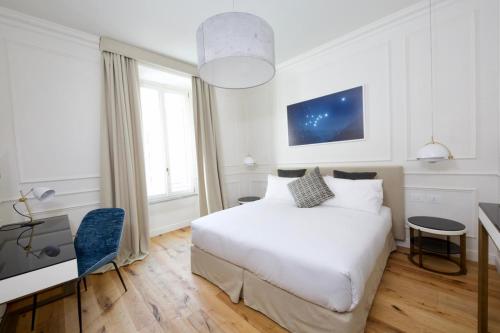 a bedroom with a white bed and a desk and window at Parisii Luxury Relais Rome-Fontana di Trevi in Rome