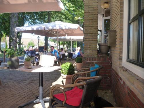 a patio with chairs and tables and an umbrella at Hotelsuites Ambrosijn in Schiermonnikoog