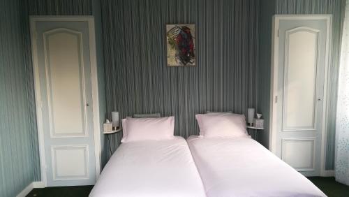 2 weiße Betten in einem Zimmer mit grünen Wänden in der Unterkunft Stretcha in Châteaubourg
