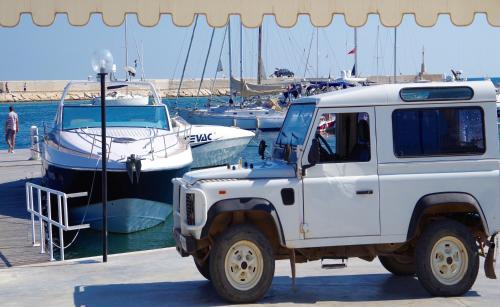 a white jeep parked next to a marina with boats at Villa Le Palme in Rosa Marina