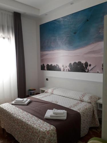 a bedroom with two beds and a painting on the wall at B&B L'Isola in Porto Cesareo