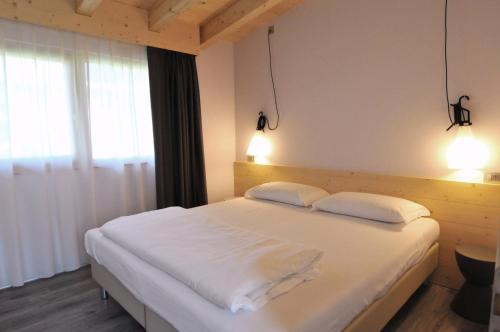 モルヴェーノにあるBungalows Chalets Lago di Molvenoのベッドルーム1室(大きな白いベッド1台、枕2つ付)
