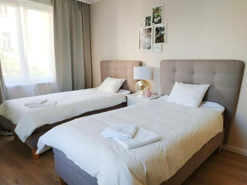 dwa łóżka w pokoju z białymi prześcieradłami w obiekcie Two-bedroom apartment 'Taupé' w Wiedniu