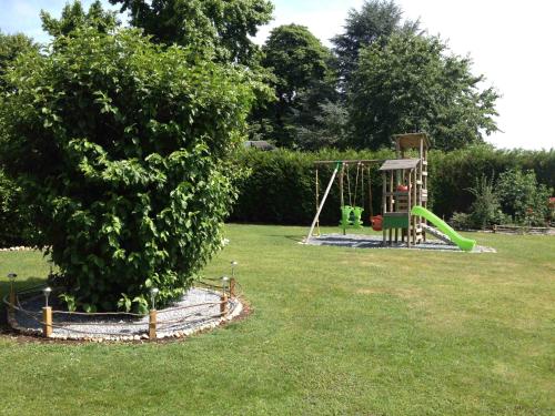 a park with a playground and a tree at Roulotte du Petit Bois in Theillement