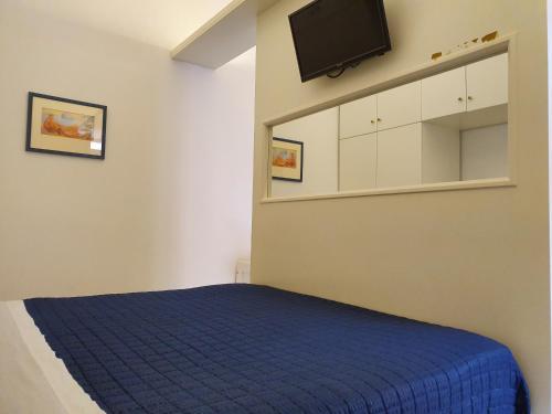 een slaapkamer met een blauw bed en een flatscreen-tv bij Vivalavida Ischia in Ischia