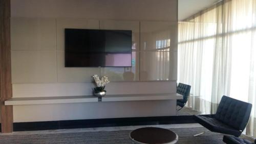 a living room with a flat screen tv on a wall at Dunamys Hotel Londrina in Londrina