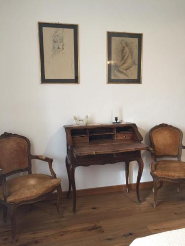 a wooden piano with two chairs and a picture on the wall at Cascina Delle Rose in Barbaresco