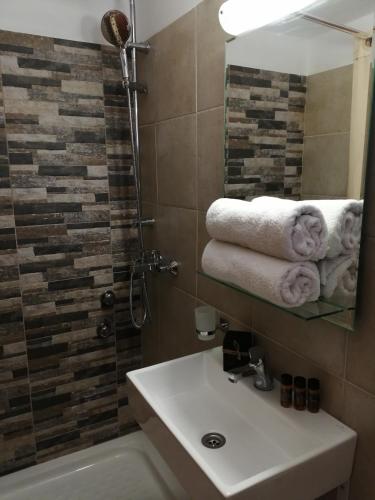 a bathroom with a sink and a shower with towels at Roza's Home and Studios in Benitses