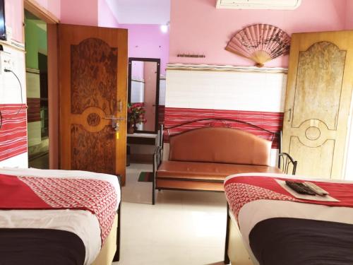 a room with two beds and a bench in it at Tirupati Lodge NJP in Siliguri
