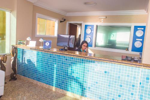 una mujer sentada en un bar en una piscina en Ocean View Hotel, en Arraial do Cabo