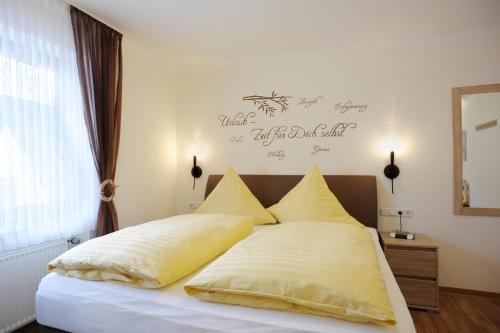 a bed with yellow pillows and a sign on the wall at Winneburger Hof in Ernst