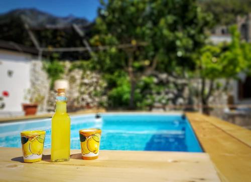 una bottiglia e tazze sedute su un tavolo accanto alla piscina di Villa Inn Costa a Tramonti